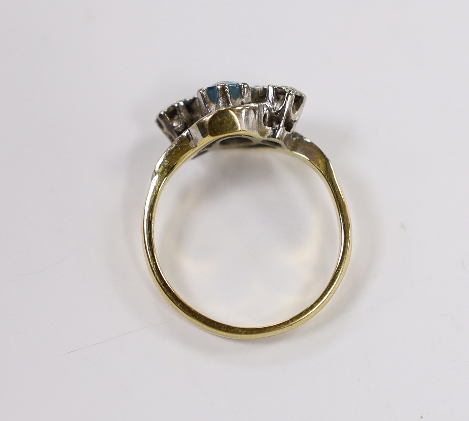 A modern 18ct gold, aquamarine and illusion set diamond three stone crossover ring, size N, gross weight 4.2 grams.